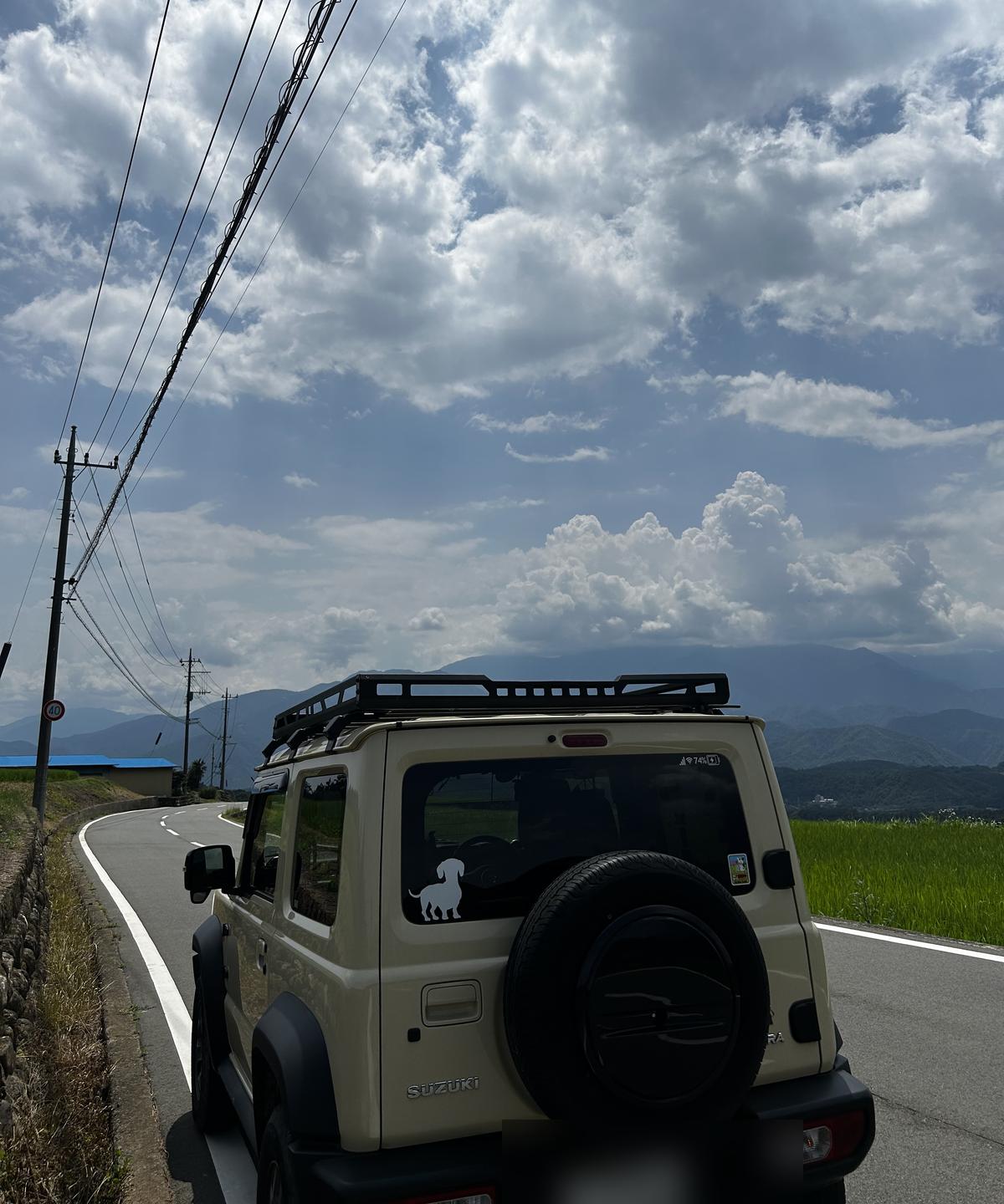田んぼ沿いの道に停まるジムニーシエラ（JB74）の後ろ姿
