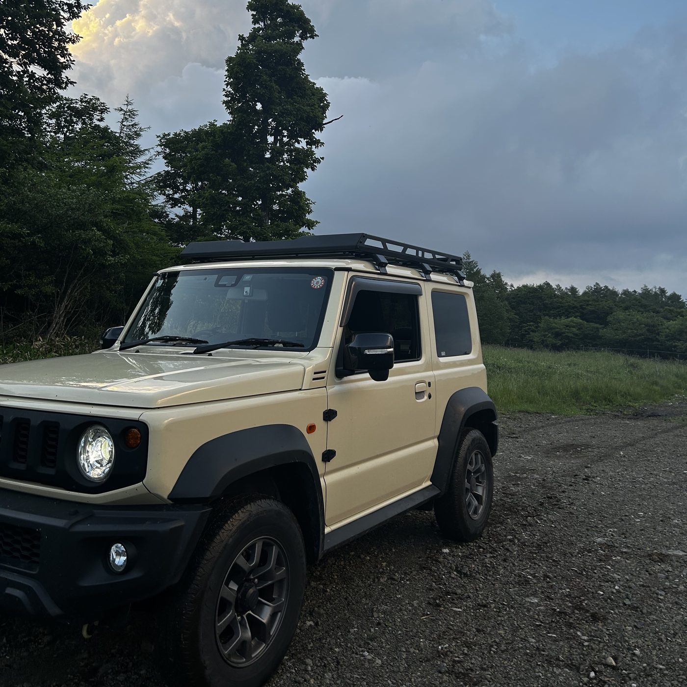森を背景にしたジムニーシエラ(JB74)。ルーフラック装着でワイルドな印象